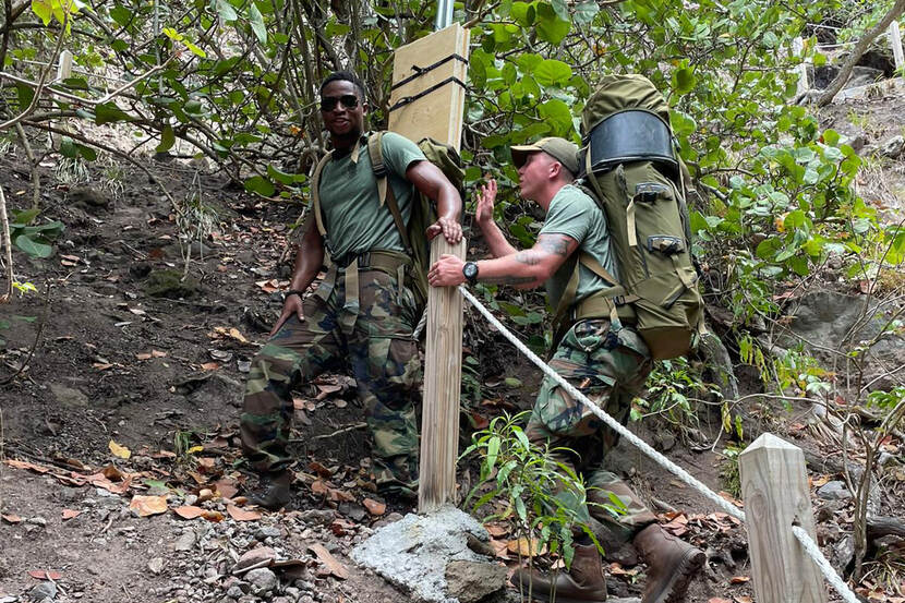 2 mariniers sjouwen materieel voor een nieuw meetstation een berg op Saba op.