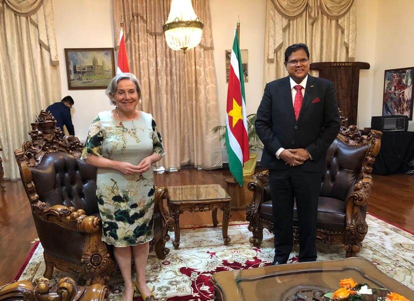 Minister Bijleveld en de Surinaamse president Chan Santokhi staan in een kamer, achter hen de Nederlandse en Surinaamse vlag.