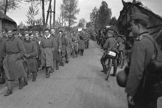 Militairen en burgers lopen in de rij. Zwart-wit foto uit Tweede Wereldoorlog
