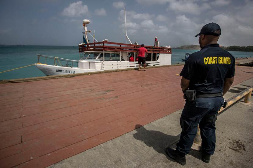 Een kustwachter staat naast een boot.