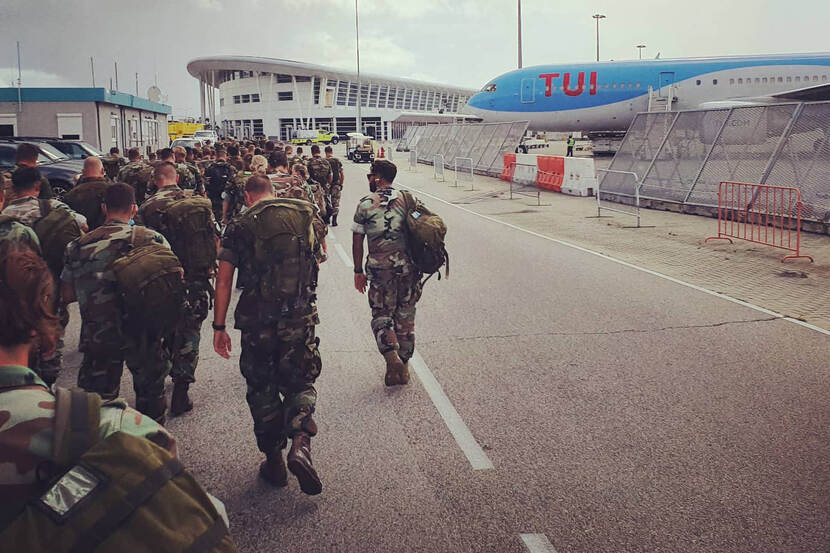 Groep militairen op de rug gezien lopen naar vliegtuig TUI.