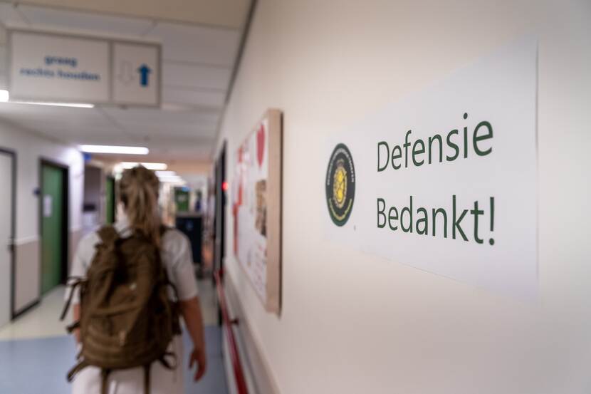 Een militair vertrekt bij het Universitair Medisch Centrum Utrecht. Aan de muur een bord met 'Defensie bedankt!'.