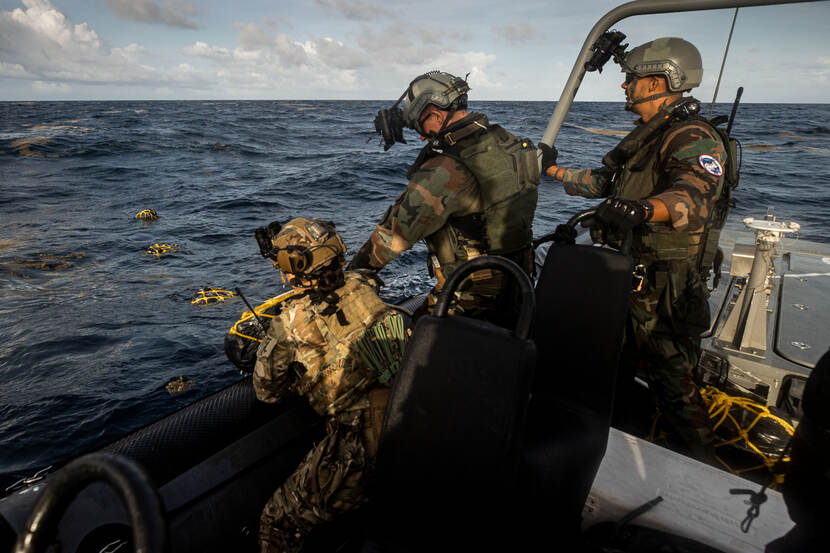 Militairen vissen drugs uit zee.