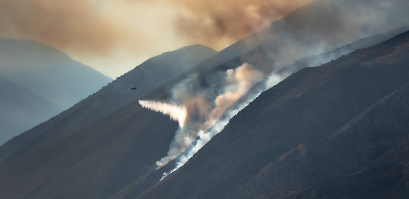 Chinook dropt water boven een natuurbrand die woedt op een berg.