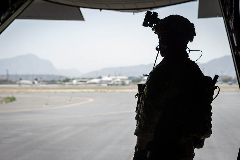 Een militair kijkt uit een vliegtuig.