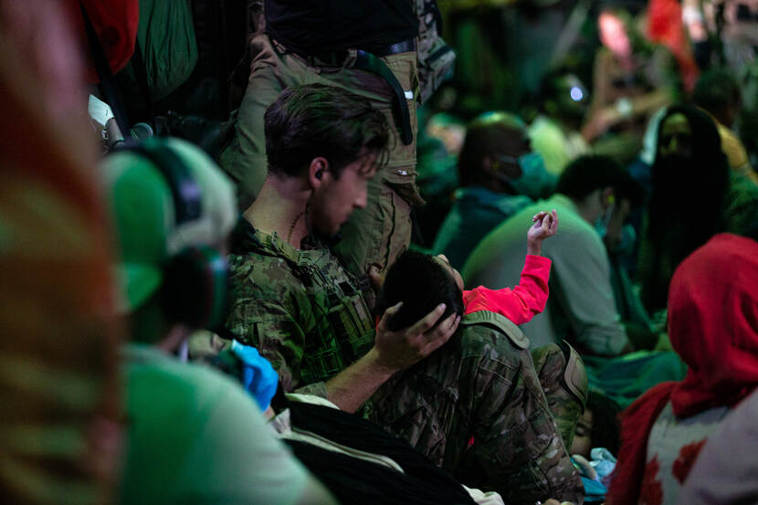 Een Nederlandse militair houdt een Afghaans kind in zijn armen tijdens een evacuatievlucht.