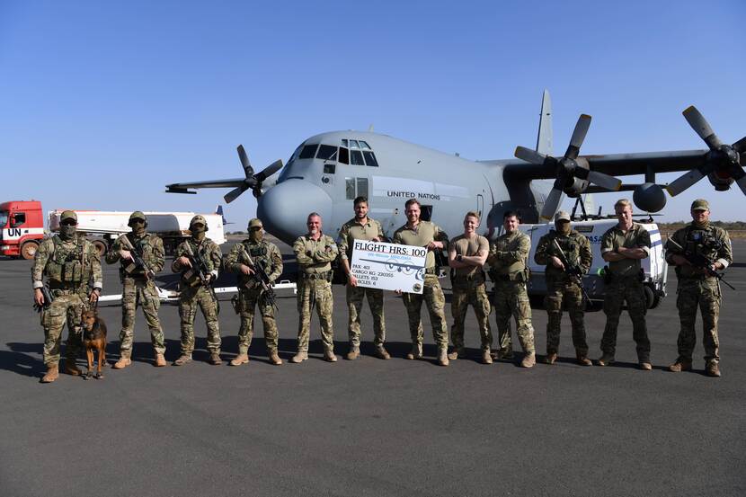Militairen poseren met bord voor C-130 Hercules
