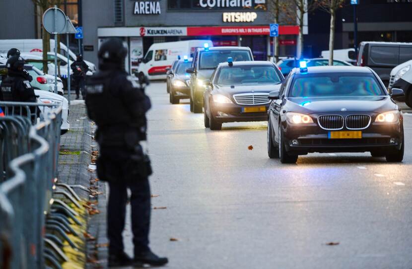 Bewapende militairen naast rij auto's.