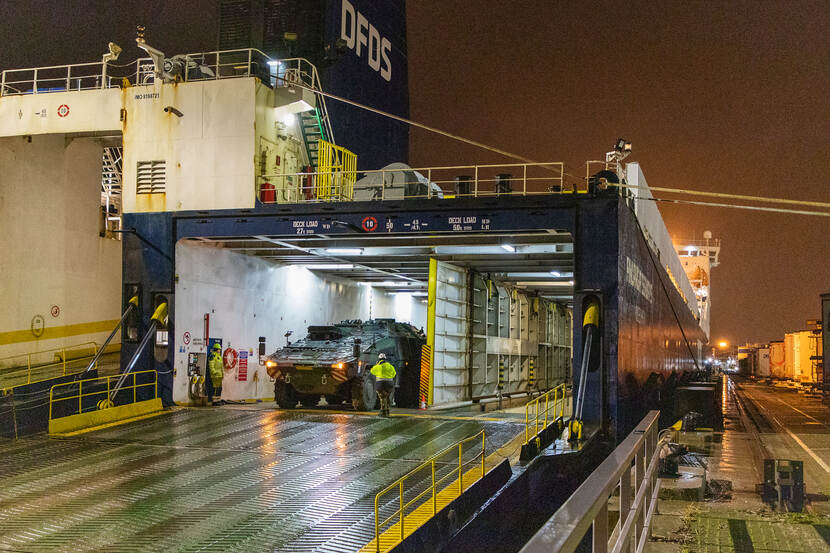 Militaire voertuigen rijden een schip uit.