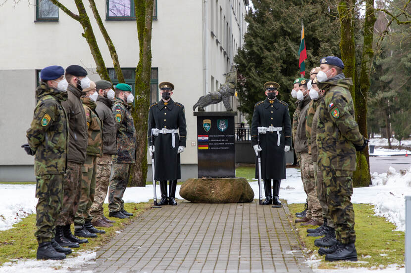 Militairen met mondkap staan opgesteld bij het monument.