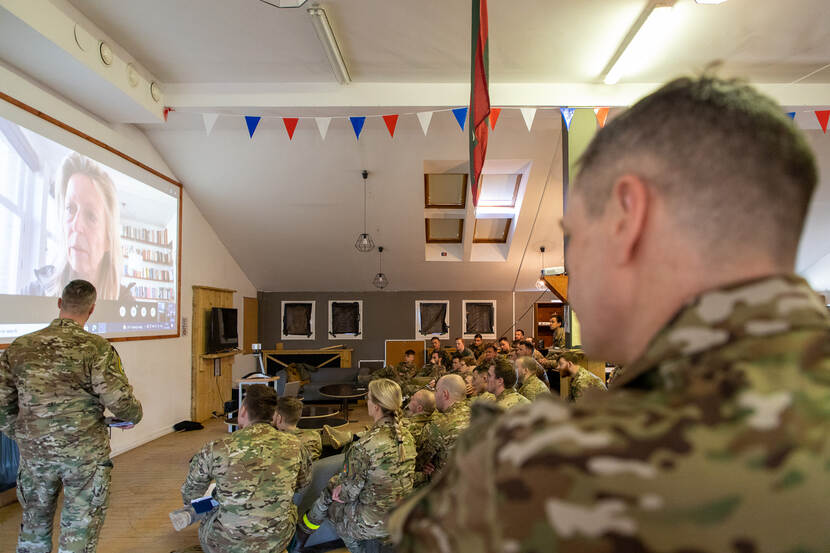 Militairen in Litouwen kijken naar een groot beeldscherm met daarop de minister van Defensie.