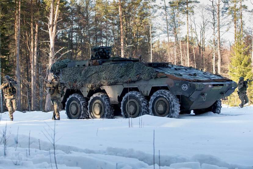 Militairen bij een Boxer, in een besneeuwd bos.