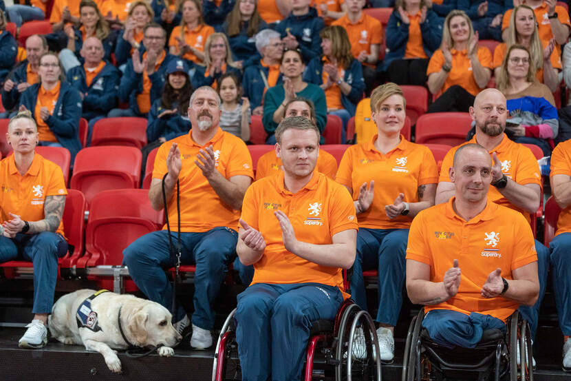 Publiek en deelnemers op de tribune klappen in hun handen.