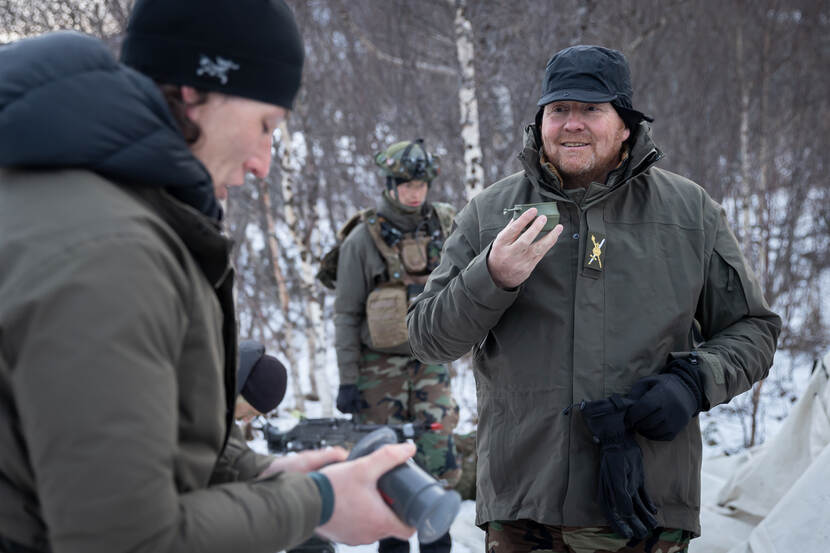 De koning drinkt thee met mariniers in sneeuw.