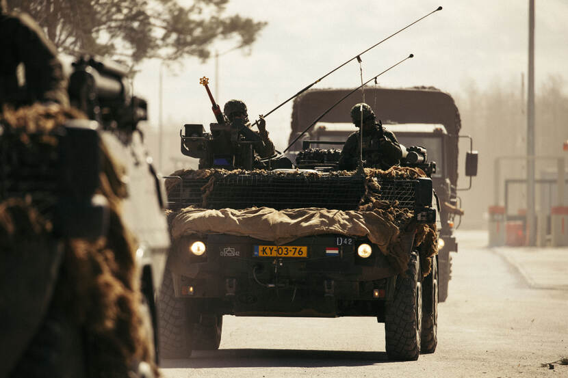 Militair voertuig met 2 militairen.
