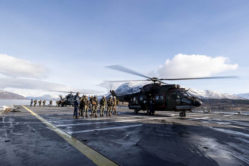 Militairen en helikopters op dek van schip.