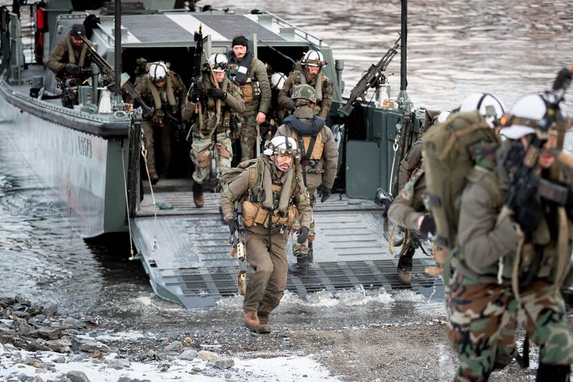 Grote groep mariniers komen aan land met een landingsvaartuig.