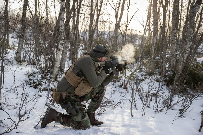 Militair met wapen in besneeuwd bos.