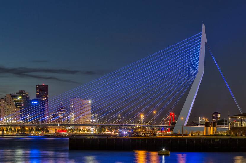 De blauw gekleurde Erasmusbrug bij nacht.