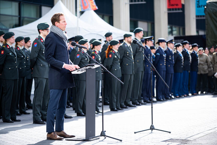 Staatssecretaris speecht bij beëdiging. Militairen staan achter hem opgesteld.