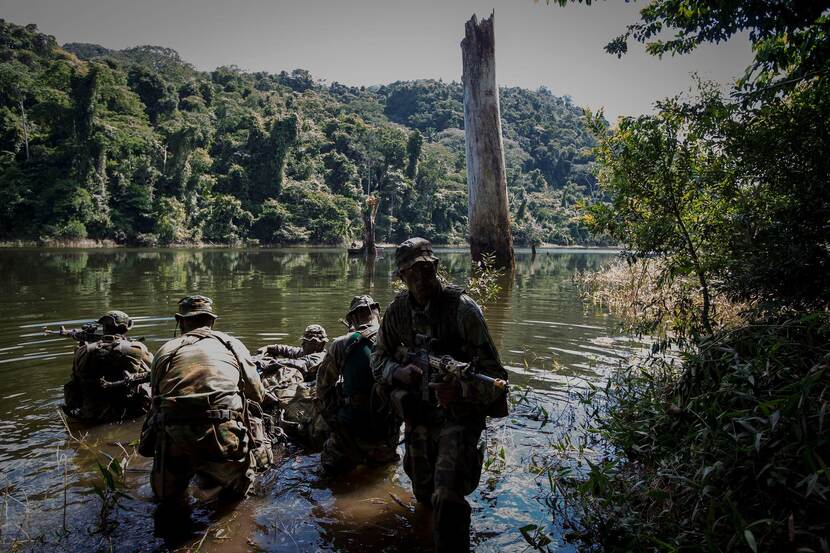 Gewapende militairen in een rivier tijdens een jungletraining in Belize.