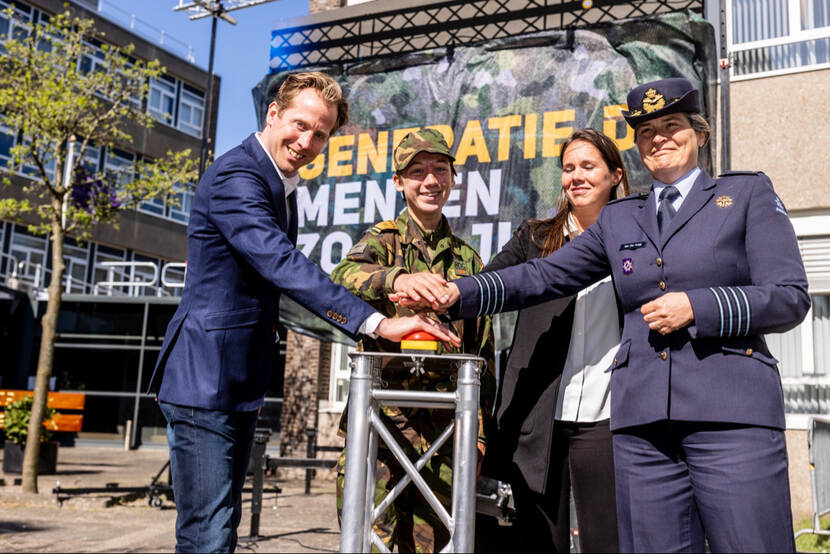 De staatssecretaris opent een wervingscampagne door op een rode knop te drukken.