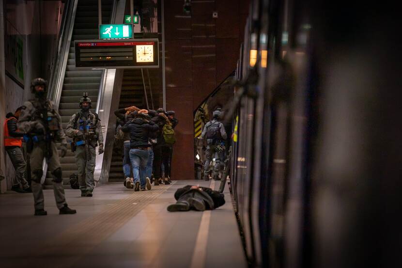 Militairen bij platform metro. Mannen met handen op hun hoofd.