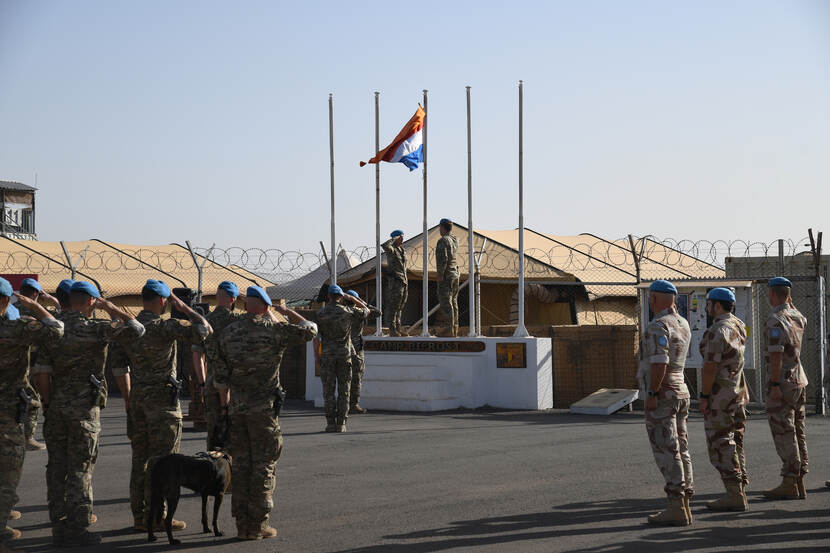 Militairen brengen groet. Nederlandse vlag met wimpel vol in top.