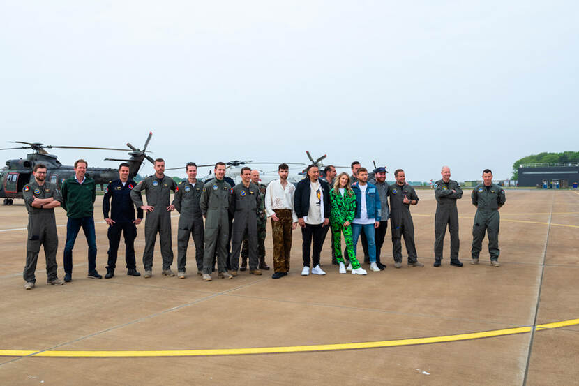 Vliegers van Defensie en de Ambassadeurs op een vliegbasis. Helikopters op de achtergrond.