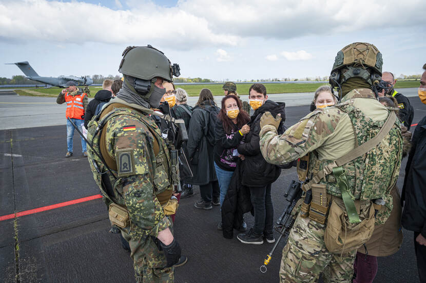 2 militairen met een rij evacues.