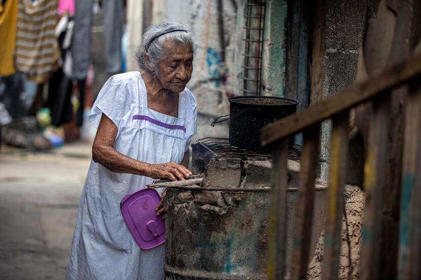 Oude vrouw bij een buitenkookplaats in een straat in Mexico.
