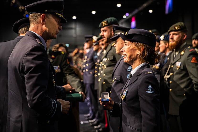 Een lachende, vrouwelijke militair met de net ontvangen herinneringsmedaille in een doosje in haar hand.