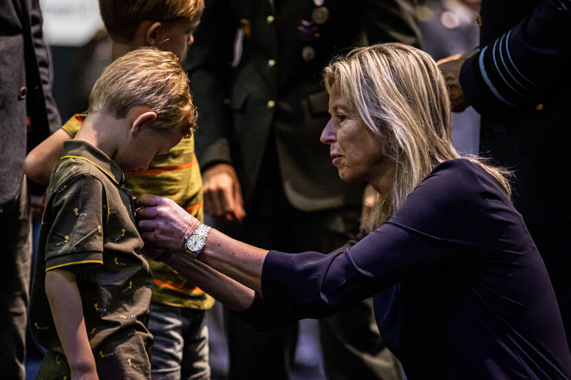 Minister Ollongren speldt een jongetje het kinder medaillon op.