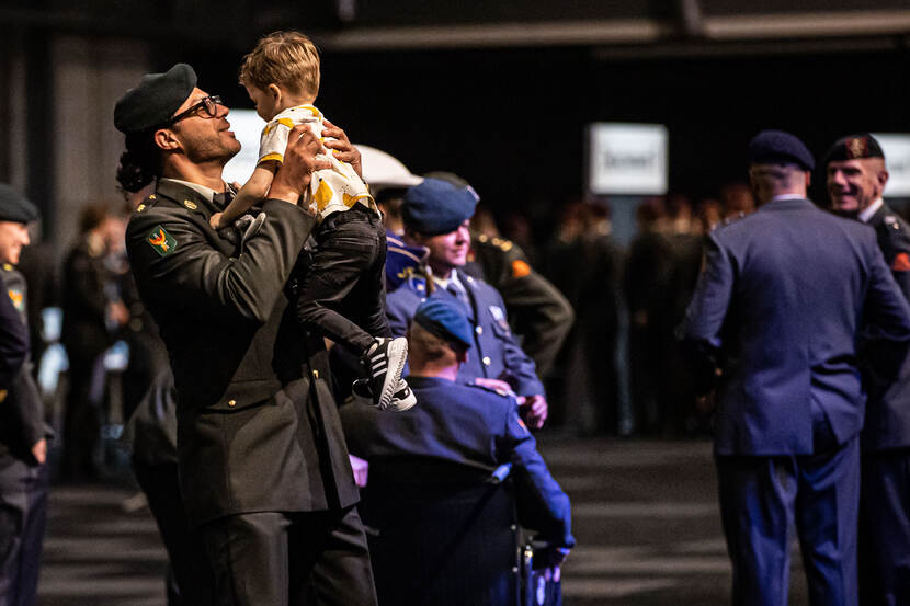 Een militair tilt zijn zoontje op aan het einde van de ceremonie.