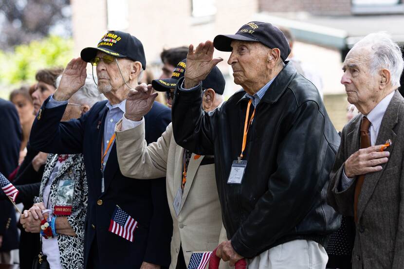 Oude mannen met Amerikaanse vlaggetje in de hand groeten.