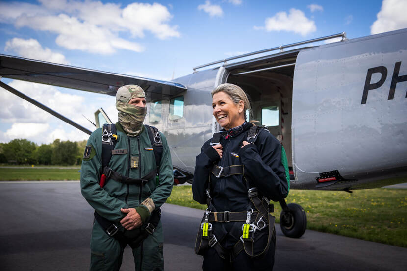 Koningin Maxima staat samen met een parachutist van het Korps Commandotroepen voor een vliegtuig.