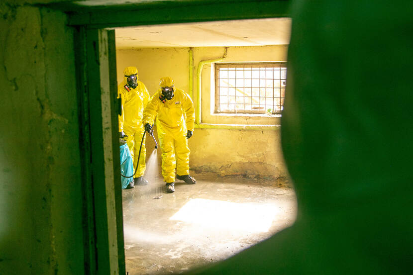 Leden van het CBRN-team in Litouwen oefenen in gele beschermende pakken.