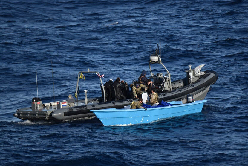 Mariniers laden balen cocaïne vanuit een klein blauw bootje over in een go-fast.