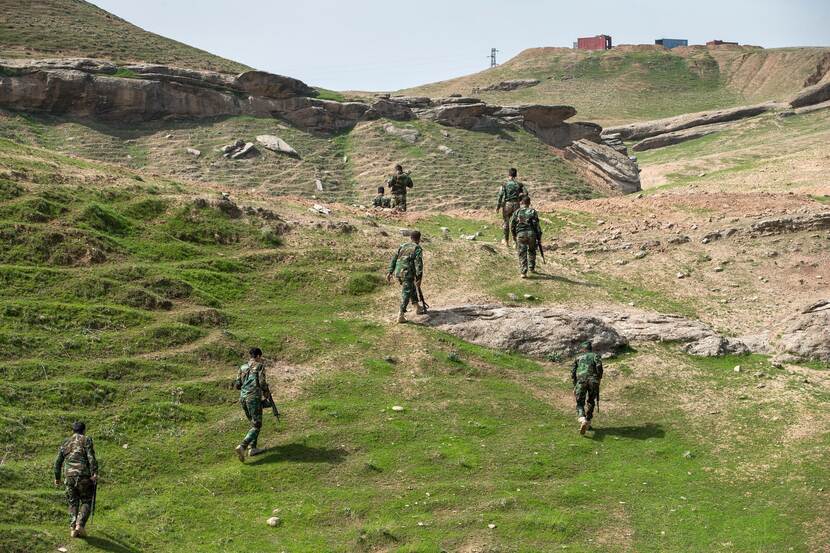 Gewapende militairen lopen over grasvlakte in Irak.