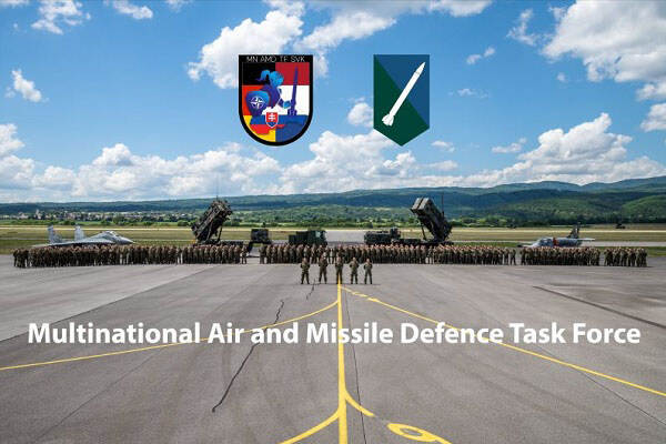 Overzichtfoto van militairen en materieel met de tekst: Multinational Air and Missile Defence Task Force.