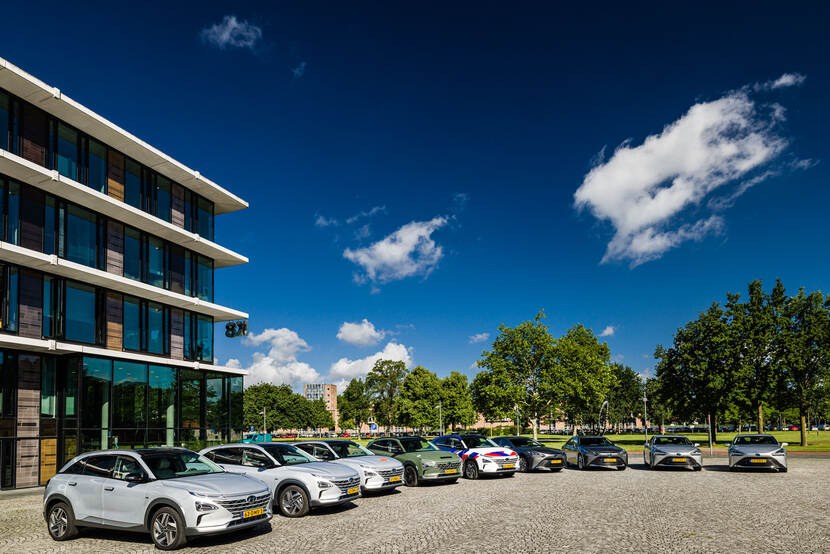 Rij voertuigen geparkeerd voor een gebouw.