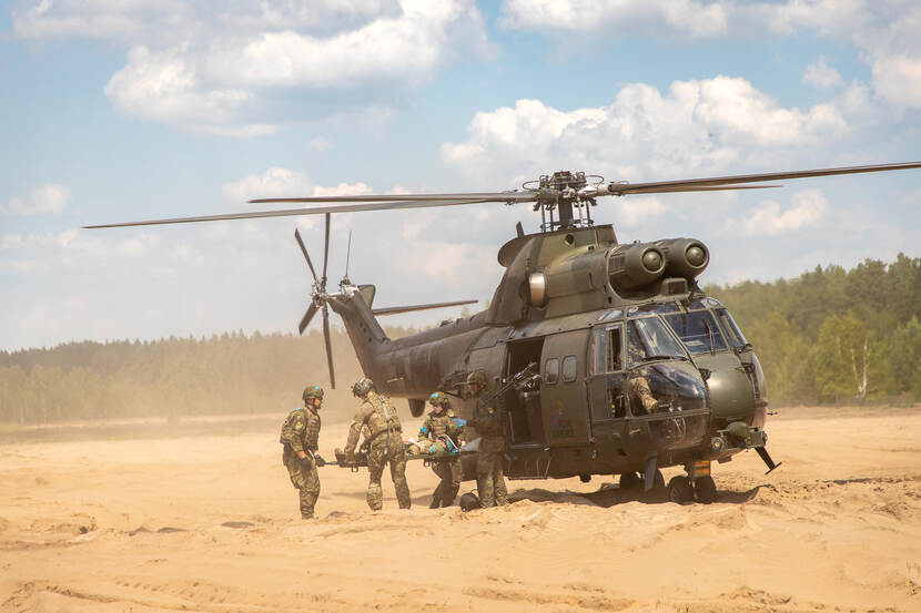 Militairen dragen gewonde in helikopter.