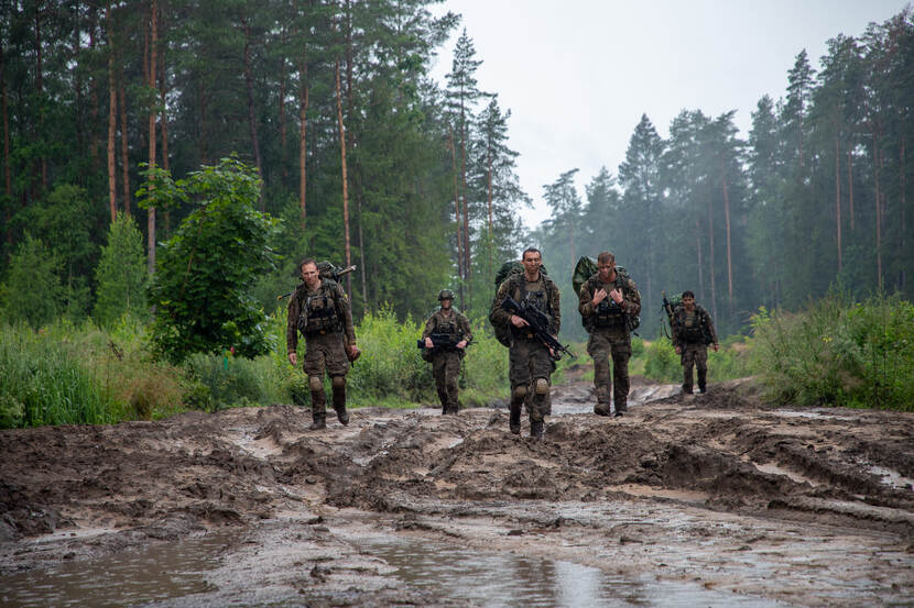 Militairen lopen door modder in een bos tijdens de training in Litouwen.