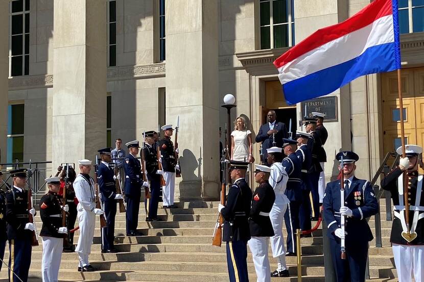 Minister Ollongren op het bordes, militairen in verschillende uniformen staan aan weerszijden van de trap. De Nederlandse vlag wappert.