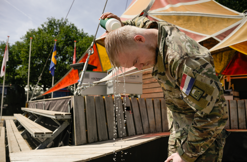 Militair giet met een fles water over zijn hoofd.