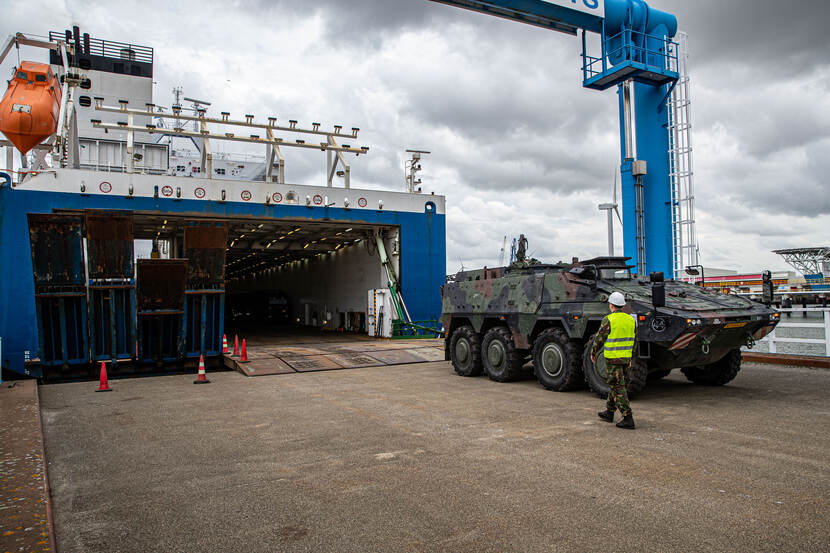 Een militair voertuig wordt een schip opgereden.