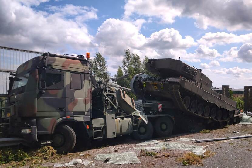 Een gecrashte truck van Defensie met daarop een tank.