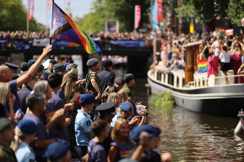 Militairen en burgers zwaaien naar een langsvarende boot op de Canal Parade.