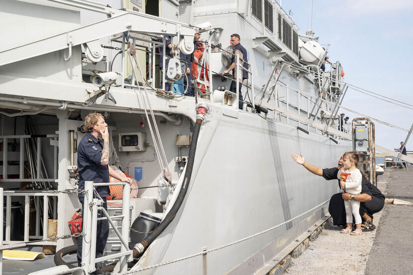 Moeder en kind op de wal sturen kushandje naar man aan boord van marineschip Zr.Ms. Vlaardingen.