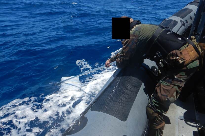 Een militair vist een baal drugs uit zee.
